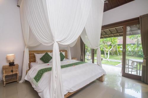 a bedroom with a white bed with a canopy at Parthi Puri Ubud in Ubud