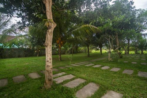 a tree in the middle of a park with a path at Parthi Puri Ubud in Ubud