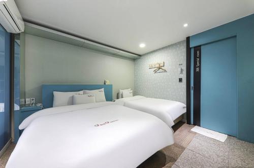 金海にある9 to 9 motelの青い壁の客室内の白いベッド2台