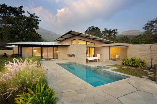 a house with a swimming pool in front of it at Dharana at Shillim All Inclusive Luxury Wellness Retreat in Lonavala