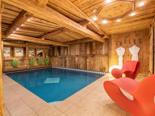 une piscine dans une maison en bois avec une chaise rouge dans l'établissement Luxueux Chalet à Courchevel avec Piscine, Hammam et Sauna - FR-1-613A-27, à Courchevel