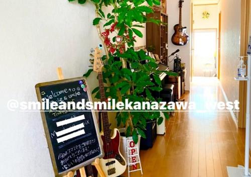 a sign in a room with a guitar and a plant at Guest House Nishikanazawa Smile & smile - Vacation STAY 12106v in Kanazawa