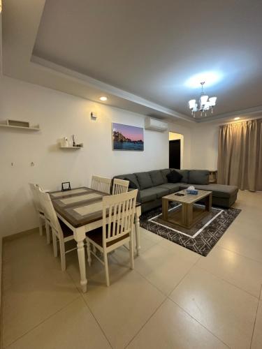 een woonkamer met een tafel en een bank bij Al Nujoom Apartment, Al Qurum in Wuţayyah