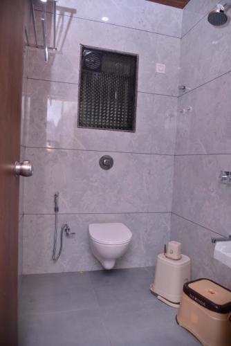 a white bathroom with a toilet and a window at Hotel D Square in Shirdi