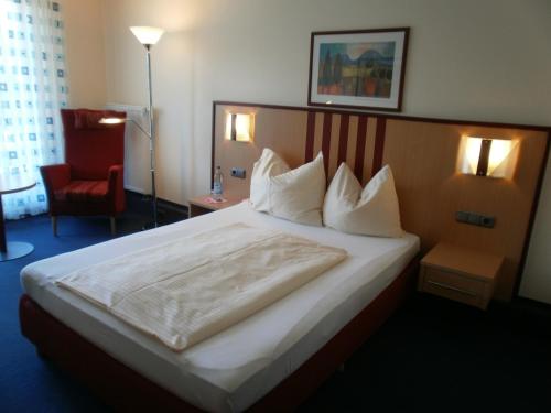 Cette chambre d'hôtel comprend un grand lit et un fauteuil rouge. dans l'établissement Apartments Aschheim, à Aschheim