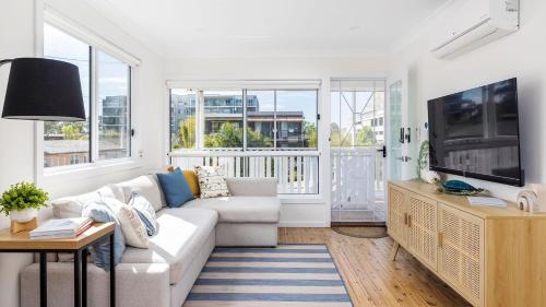 a living room with a couch and a tv at Shoal Bay Beach House Three in Shoal Bay