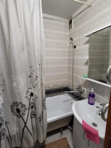 ein Badezimmer mit einem Duschvorhang, einem Waschbecken und einer Badewanne in der Unterkunft 3-х комнатная по ул. Есенова 19А in Qysylorda