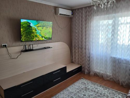 sala de estar con TV de pantalla plana en la pared en 3-х комнатная по ул. Есенова 19А, en Kyzylorda