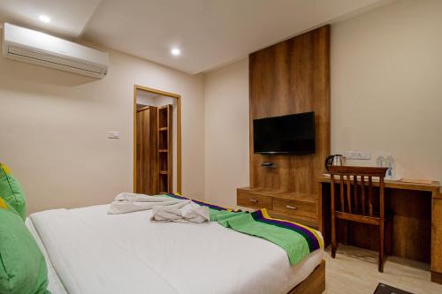 a bedroom with a bed and a desk and a television at Treebo Trend Sonal Palace 1 Km From Jodhpur Airport in Jodhpur