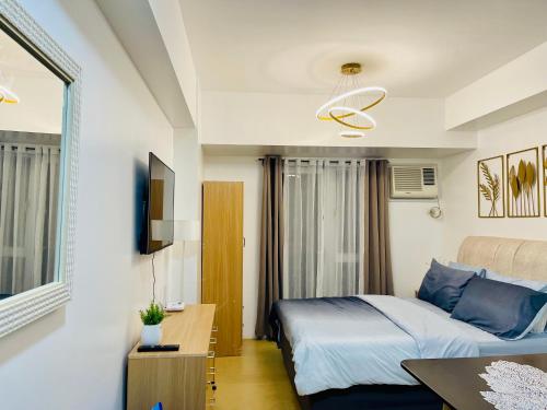 Schlafzimmer mit einem Bett, einem Schreibtisch und einem TV in der Unterkunft Studio Unit with Balcony at Centrio Towers beside Ayala Mall Downtown CDO in Cagayan de Oro