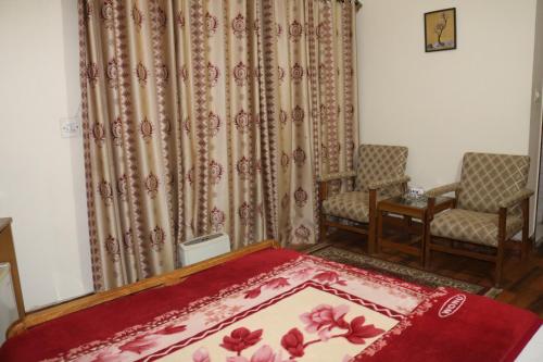 a room with two chairs and a bed and a rug at The City Lodge in Islamabad