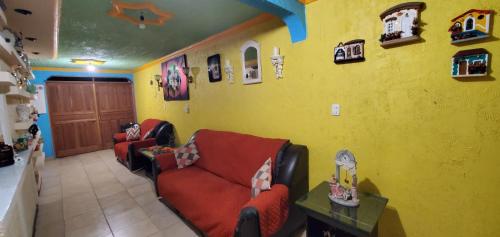 een woonkamer met 2 banken en een gele muur bij House of Irma in Santa María Chimalhuacán