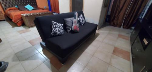 een zwarte stoel met kussens in de woonkamer bij House of Irma in Santa María Chimalhuacán