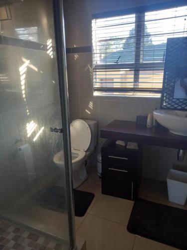 a bathroom with a toilet and a sink and a shower at Queens and king2 in Pinetown