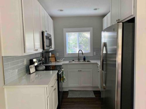 a kitchen with white cabinets and a stainless steel refrigerator at StA Hideaway - Upper Unit Apt Minutes From Beach in Saint Augustine