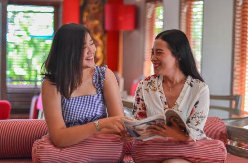 two women sitting on a bench reading a book at Rama Residence Petitenget in Seminyak