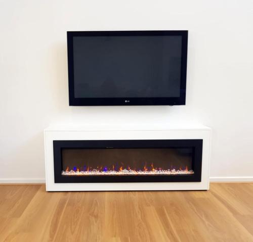 a living room with a fireplace with a tv above it at Normanville Getaway House in Normanville