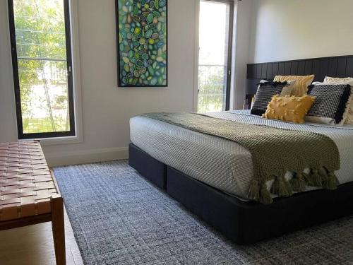 a bedroom with a large bed and two windows at Hyams Beach House B - Brand new lux beach oasis in Hyams Beach