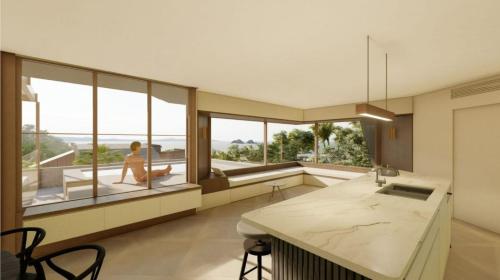 a kitchen with large windows and a woman sitting on a bench at Moonrise & Starfall in Byron Bay