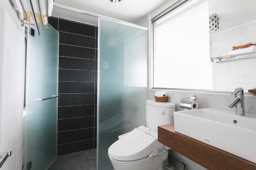a bathroom with a toilet and a sink and a shower at Tropical Low Boundary B&B in Donghe