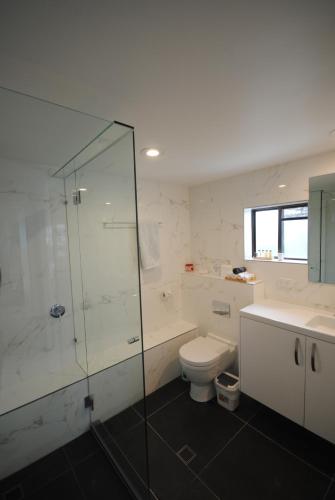 a bathroom with a glass shower and a toilet at Albatross North Apartments in Gold Coast
