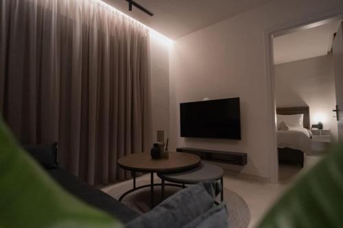 a living room with a television and a table and a bed at ID Residences 102 in Volos