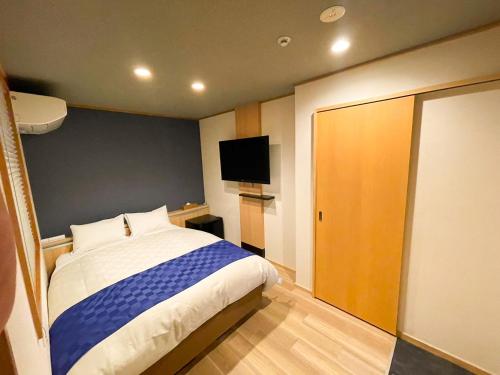 1 dormitorio con 1 cama y TV de pantalla plana en NK Hotels, en Fukuoka