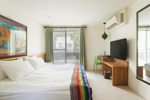 a bedroom with a bed with a television and a desk at Tropical Low Boundary B&B in Donghe