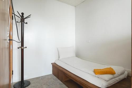 a bed in a room with a white wall at Tropical Low Boundary B&B in Donghe