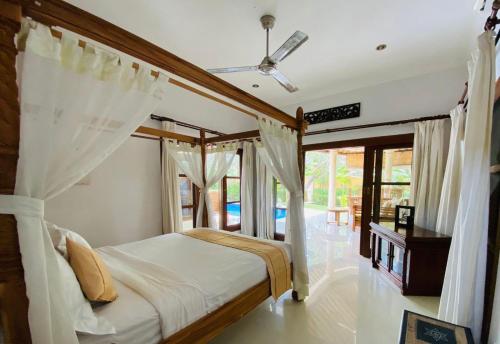 a bedroom with a canopy bed with curtains at Bali Jade Villas in Sanur