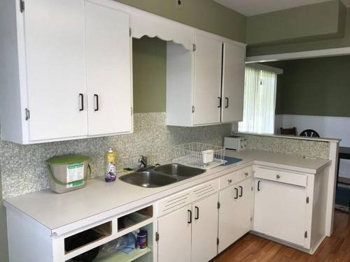 a kitchen with white cabinets and a sink at Farm House - L&S Farms in Chilliwack