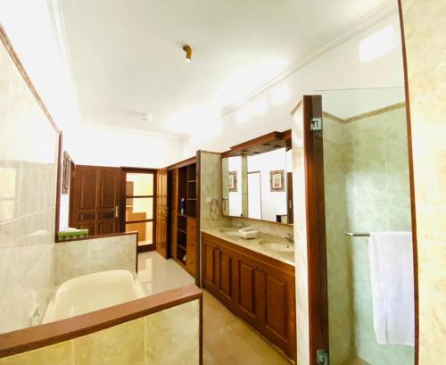 uma casa de banho com uma banheira, um lavatório e um espelho. em Bali Jade Villas em Sanur