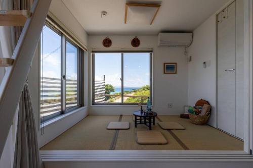 a room with a large window with a view of the ocean at NEW！パノラマオーシャンビューのテラスジャグジーは圧巻。新築２階建て吹抜け天井リビングは開放感抜群 in Sesoko