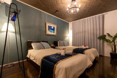 a hotel room with two beds and a lamp at NEW！パノラマオーシャンビューのテラスジャグジーは圧巻。新築２階建て吹抜け天井リビングは開放感抜群 in Sesoko