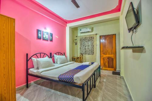 a bedroom with a pink wall with a bed at Downtown in Calangute
