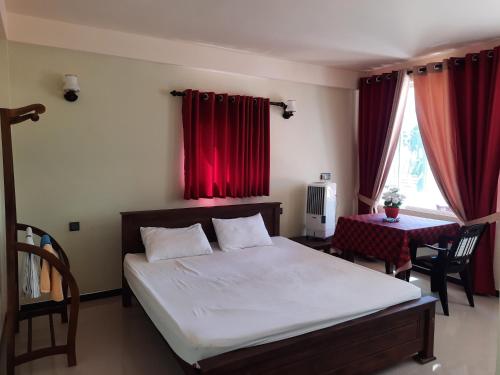 1 dormitorio con 1 cama con cortinas rojas y mesa en Eventide Beach Resort en Marawila