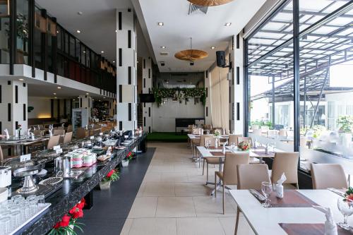 a restaurant with tables and chairs and windows at Grand Ratchapruek Hotel in Ban Bang Phlap