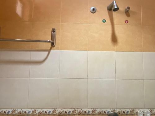 y baño con ducha y pared de azulejos. en OYO 90896 Gold Hill Hotel en Jerantut