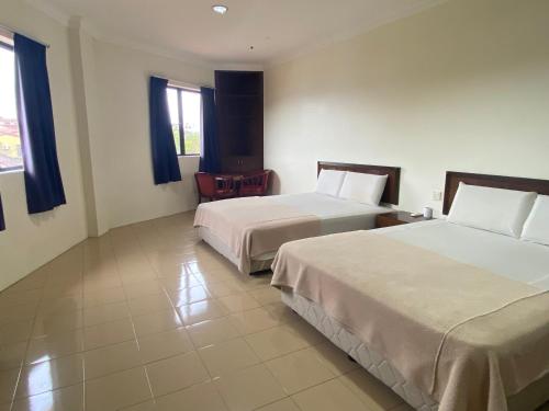 una camera d'albergo con due letti e una sedia di OYO 90896 Gold Hill Hotel a Jerantut