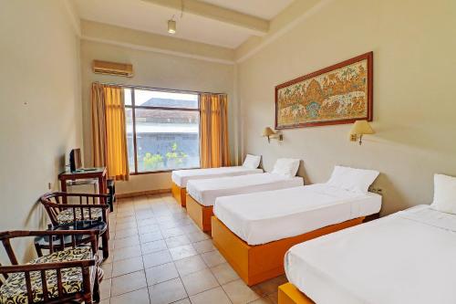 a hotel room with three beds and a window at SUPER OYO 91870 Warna Kedaton in Denpasar