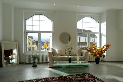 a living room with windows and a couch and a table at Goldener Löwe in Bodman-Ludwigshafen