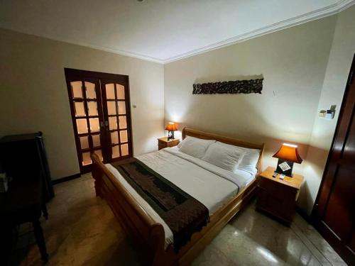 a bedroom with a bed and two lamps and a window at Villa Layang Bulan - Male Only in Denpasar