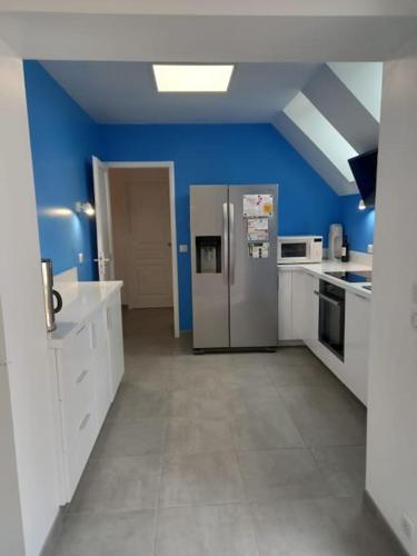- une cuisine avec des murs bleus et un réfrigérateur dans l'établissement Maison 3 chambres circuit des 24h Le Mans, au Mans