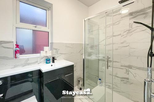 ein Bad mit einem Waschbecken und einer Glasdusche in der Unterkunft Live In Style House In Desirable Location in Manchester