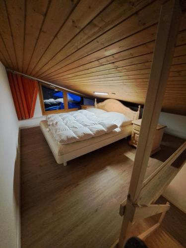 Cama en habitación con techo de madera en I dr Rehwiesa B31, en Arosa
