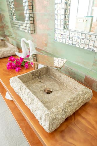 a stone sink on a wooden table with flowers at La Perla Bianca - 1 BR Beachfront Luxury Villa offering utmost privacy in Les Terres Basses