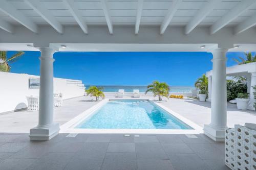 a swimming pool with the ocean in the background at La Perla Bianca - 1 BR Beachfront Luxury Villa offering utmost privacy in Les Terres Basses