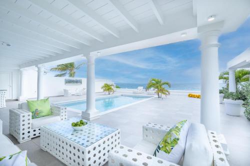 an outdoor patio with a swimming pool and the ocean at La Perla Bianca - 1 BR Beachfront Luxury Villa offering utmost privacy in Les Terres Basses
