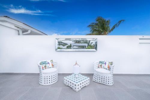 a white patio with two chairs and a table at La Perla Bianca - 1 BR Beachfront Luxury Villa offering utmost privacy in Les Terres Basses