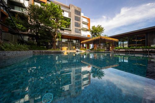 a swimming pool in front of a building at Richmann Resort Hotel Hatyai in Hat Yai